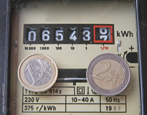 Photo: electricity meter with two coins of one and two euros electricity meter with two coins of one and two euros