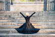 Young beautiful ballerina with black long dress posing on stairs