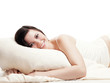 Pretty smiling young woman is lying on her pillow - isolated