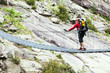 Woman trekking with backpack crossing bridge