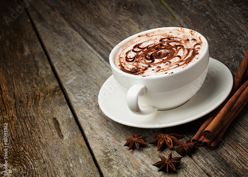 Photo: coffee cup and beans, cinnamon sticks, nuts and chocolate on woo coffee cup and beans, cinnamon sticks, nuts and chocolate on woo