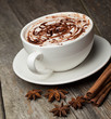 coffee cup and beans, cinnamon sticks, nuts and chocolate on woo