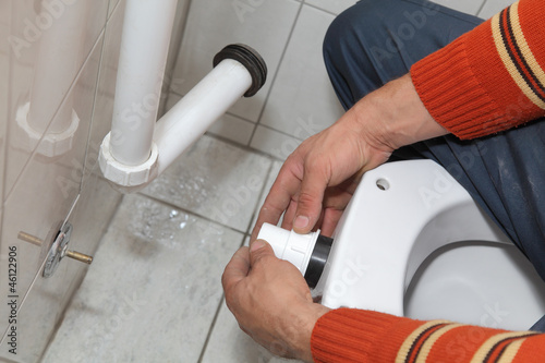 Photo: Plumber fixing plastic tube, wall mounted toilet cistern Plumber fixing plastic tube, wall mounted toilet cistern