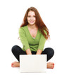 A smiling woman with a laptop on the floor