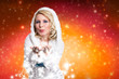 junge blonde Frau im Winteroutfit pustet Schnee