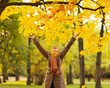 Happy woman throwing fallen leaves