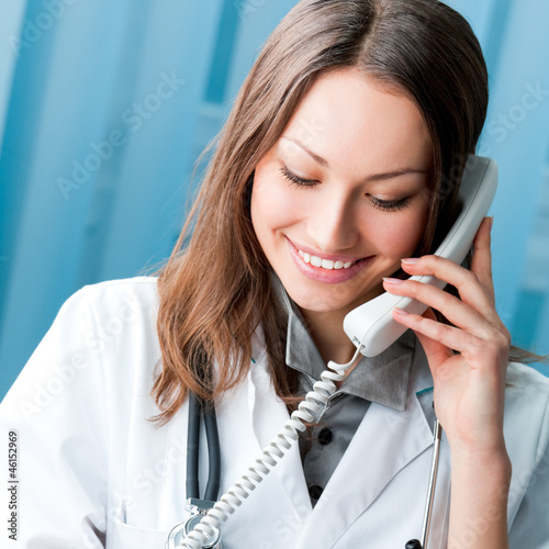 Photo: Young doctor on phone, at office Young doctor on phone, at office