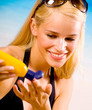 Foto: Young woman with sun protection cream on beach Young woman with sun protection cream on beach