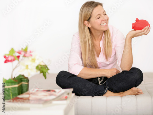 Photo: Frau mit Sparschwein auf der Couch Frau mit Sparschwein auf der Couch