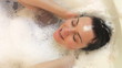 Overhead View Of Woman Washing Hair In Bubble Filled Bath