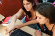 Latin mother teaching her young daughter how to use a computer