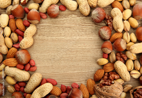Photo: assortment of tasty nuts on wooden background assortment of tasty nuts on wooden background