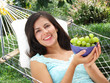 Joven mujer comiendo uvas.Descansando en una hamaca.