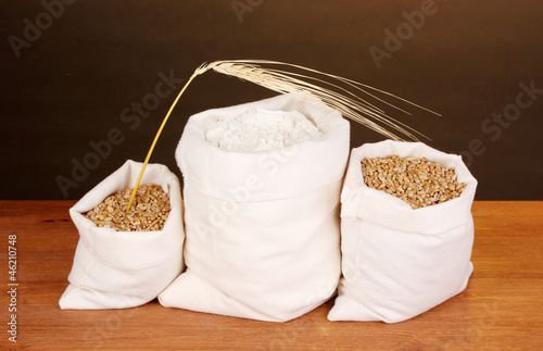 Photo: Flour and wheat grain on wooden table on dark background Flour and wheat grain on wooden table on dark background