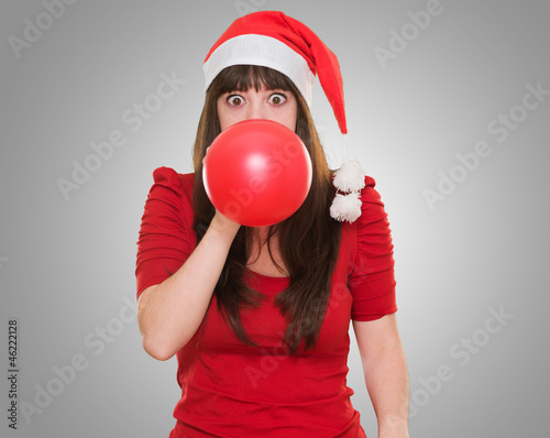 Photo: woman blowing balloon and wearing a christmas hat woman blowing balloon and wearing a christmas hat