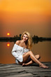 beautiful girl with a white shirt on the pier at sunset