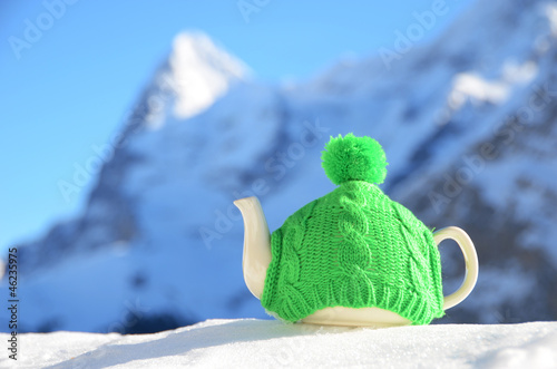 Photo: Tea pot in the knitted cap on the snow Tea pot in the knitted cap on the snow