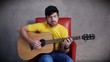 Video: Musician in hat sitting on red armchair playing on guitar Musician in hat sitting on red armchair playing on guitar