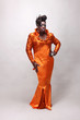 Drag queen wearing an orange gown with sequins.