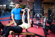 Young woman doing sit ups with the help of a personal trainer. S