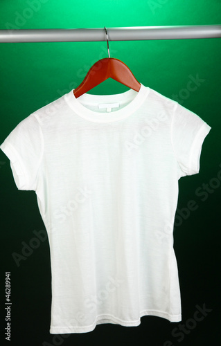 Photo: White t-shirt on hanger on green background White t-shirt on hanger on green background
