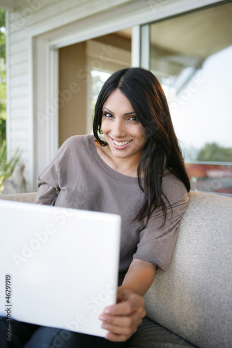 Photo: beautiful brunette sitting in the back yard with her laptop beautiful brunette sitting in the back yard with her laptop