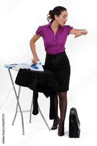 Photo: Businesswoman ironing and looking at the time Businesswoman ironing and looking at the time