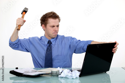 Photo: businessman ready to smash his laptop with a hammer businessman ready to smash his laptop with a hammer