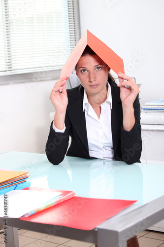 Photo: Young woman hiding under a file Young woman hiding under a file
