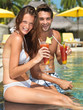Young couple enjoying cocktail by the poolside