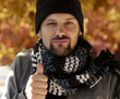 Uomo con sciarpa e cappello segna ok