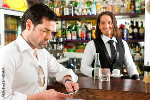 Photo: Barista mit Gast in seinem Cafe oder Coffeeshop Barista mit Gast in seinem Cafe oder Coffeeshop