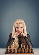 Photo: Beautiful blonde woman playing chess on dark background. Beautiful blonde woman playing chess on dark background.