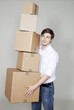Handsome young man holding stack of cardboard boxes