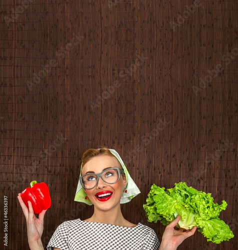 Photo: Funny woman cook holding salad and sweet pepper Funny woman cook holding salad and sweet pepper