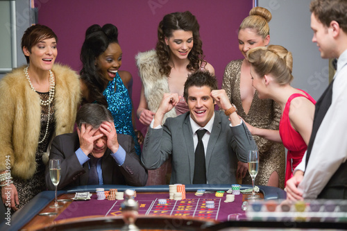Photo: Man winning as another is losing at roulette table Man winning as another is losing at roulette table