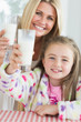 Photo: Mother and daughter raising milk glasses Mother and daughter raising milk glasses