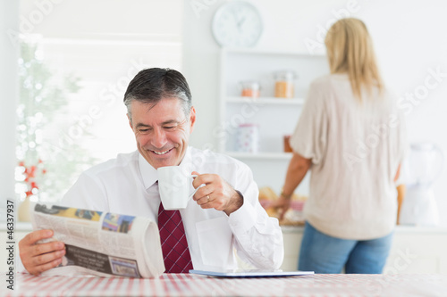 Photo: Man smiling while reading newspaper before work Man smiling while reading newspaper before work