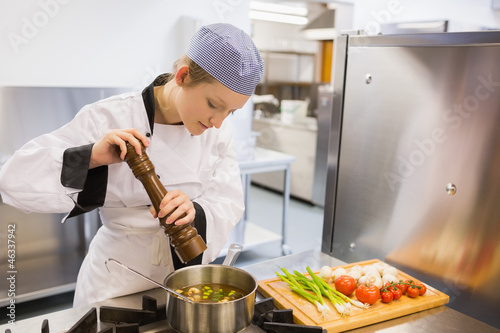 Photo: Woman spicing soup in kitchen Woman spicing soup in kitchen