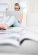 Woman sitting on the couch while using laptop and calling