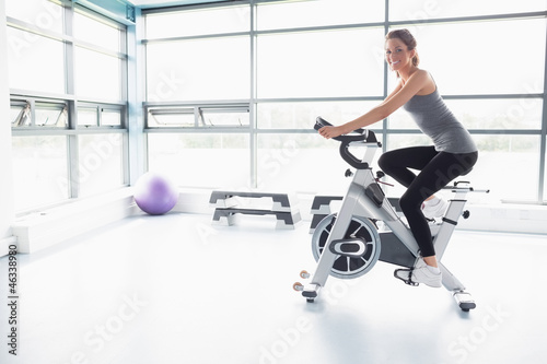 Photo: Happy woman riding an exercise bike Happy woman riding an exercise bike