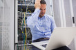 Man getting stressed with laptop over servers