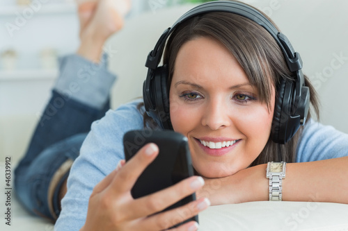 Photo: Woman using her smartphone and listening to music Woman using her smartphone and listening to music