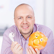 lächelnder mann mit sparschwein und stromstecker