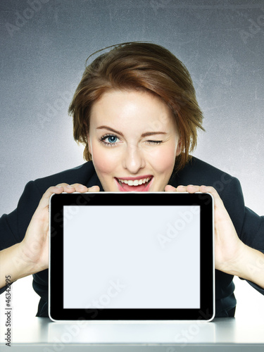 Photo: Business woman winking over her tablet pc with copyspace Business woman winking over her tablet pc with copyspace
