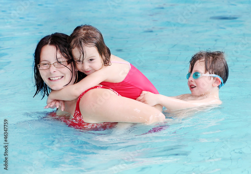 Photo: Happy family playing in a swimming pool. Happy family playing in a swimming pool.