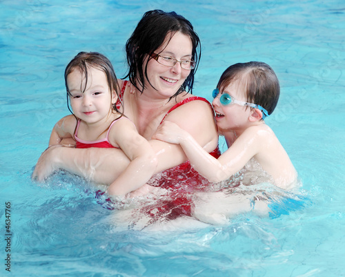 Photo: Happy family playing in a swimming pool. Happy family playing in a swimming pool.
