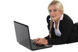 woman in a suit lying and working on her laptop