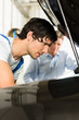 Kunde und Mechaniker an Auto schauen unter Haube