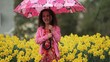 Video: Smiling young mixed race girl with umbrella extending arm in rainy daffodil field Smiling young mixed race girl with umbrella extending arm in rainy daffodil field